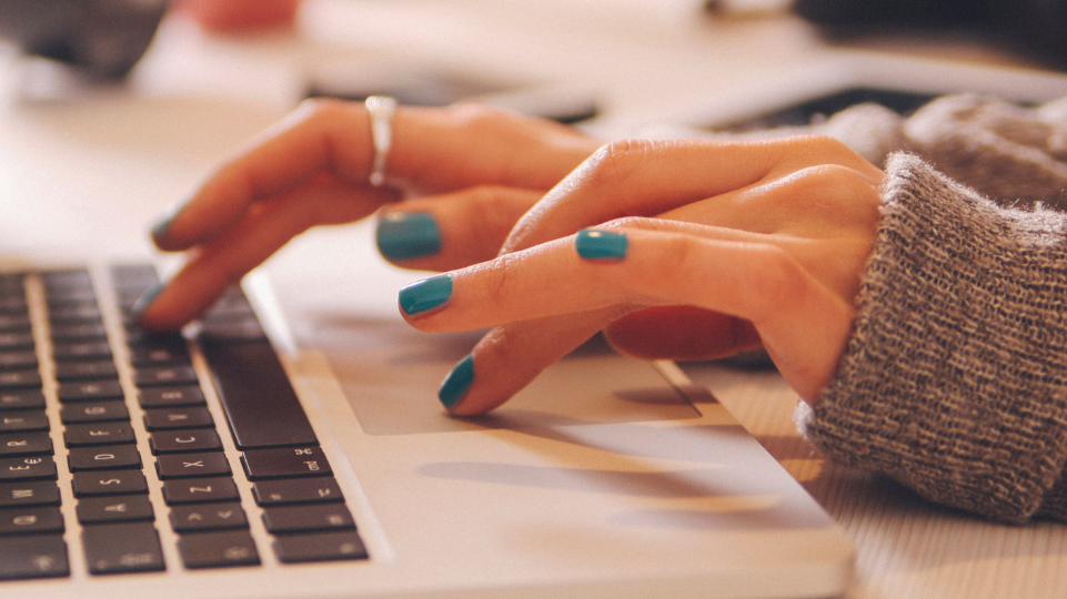 The image shows a person's hands typing on a laptop