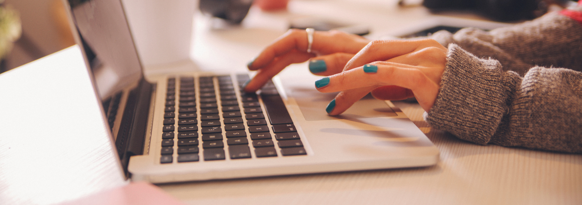 The image shows a person's hands typing on a laptop.