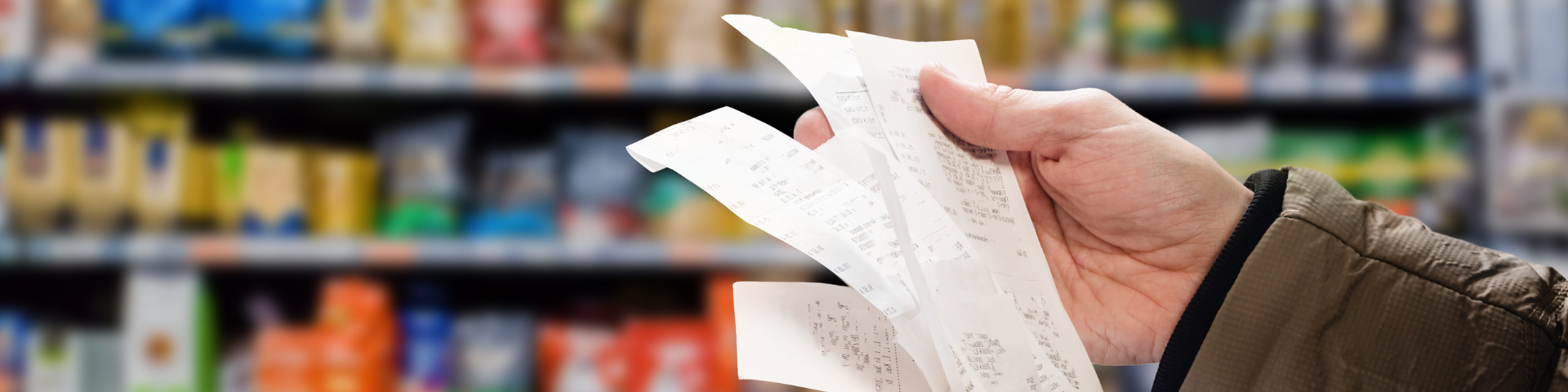 A person's hand holding receipts