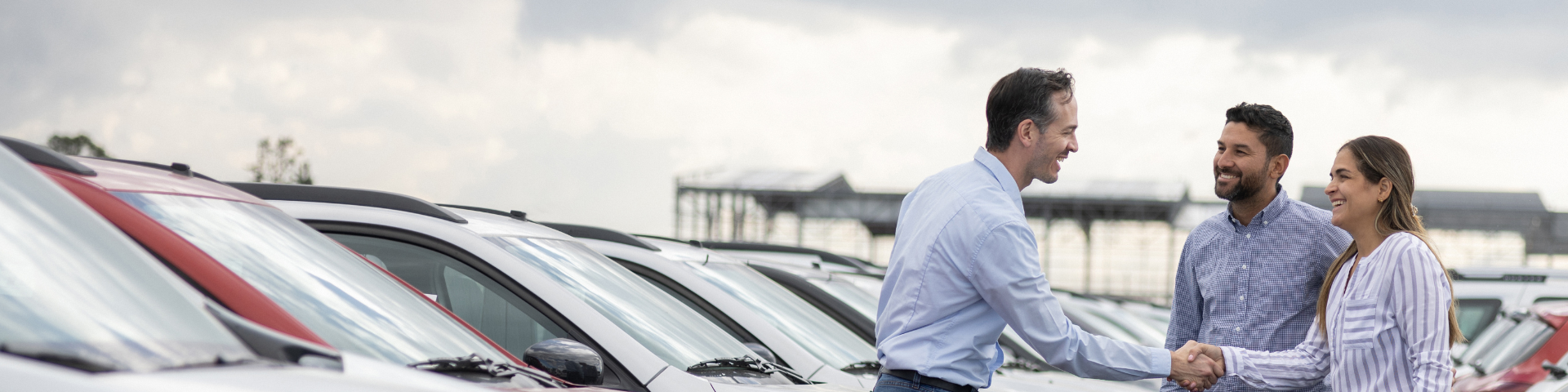 A woman shakes hands with a man in a car dealership