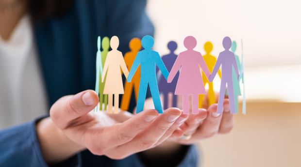 Hands holding small cardboard cut outs of people