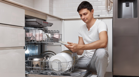 A person is unpacking their dishwasher and looking unhappy