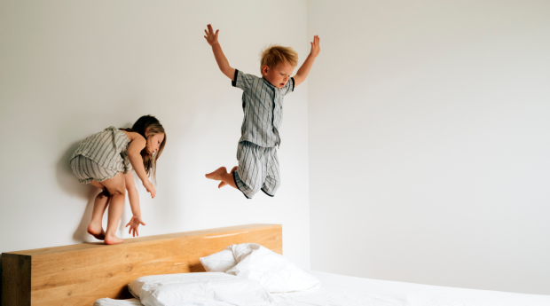 2 children jumping on a bed