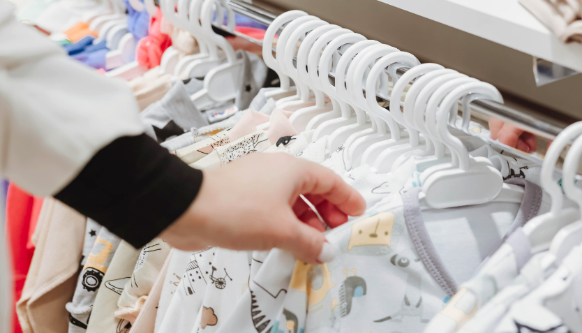 A person looking through a rail of children's clothes