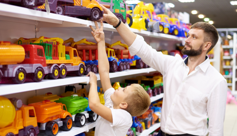 A man and a child looking at toys in a toy shop