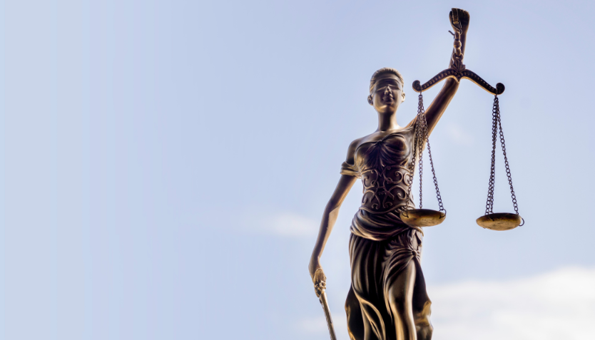 The statue of justice holding the scales against a blue sky background