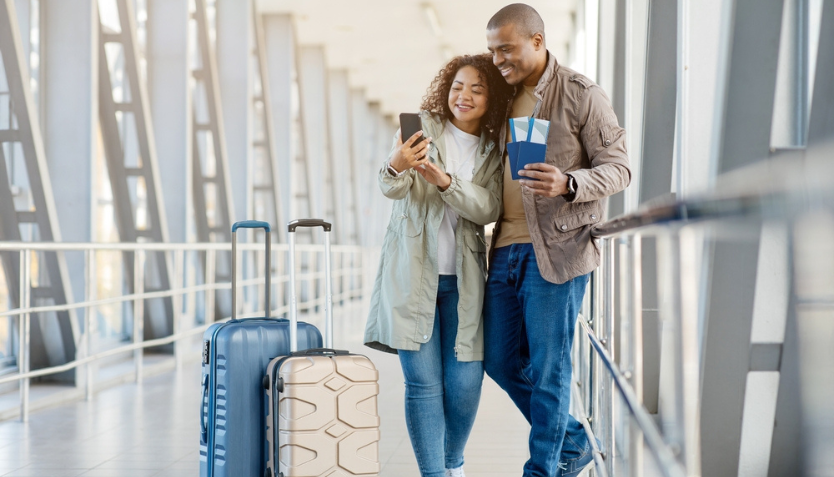 Couple at the airport holding their luggage and boarding passes.