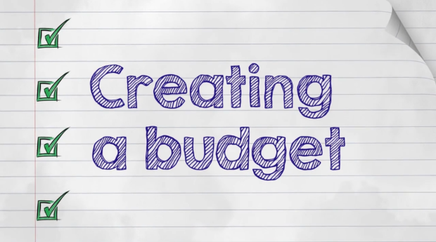 A copybook with the text 'create a budget' written in blue pen