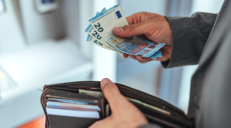 Man taking three 20 euro notes from an atm and into his wallet.