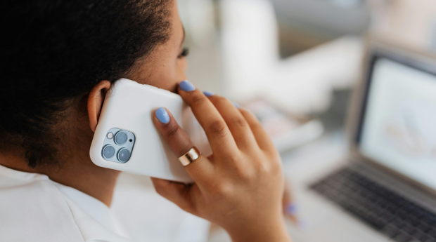 Woman in front of an open laptop, on her mobile phone.