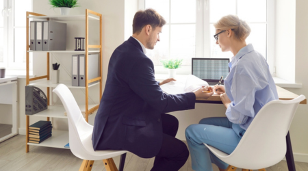 Man and woman sitting down, reviewing notes in front of an open laptop.