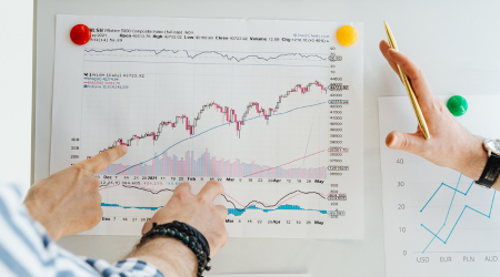 Shows people pointing at a graph hanging on a wall.