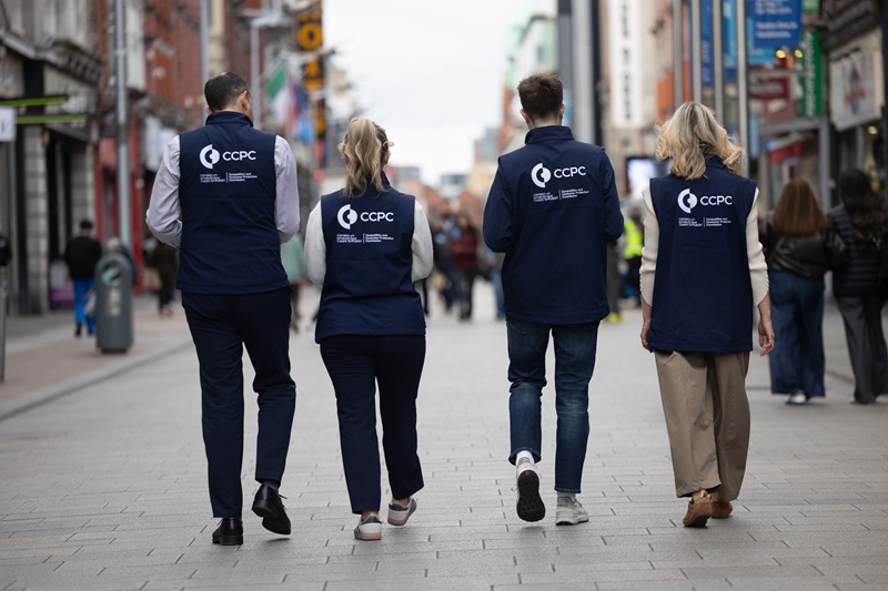 Four CCPC workers walking away from the camera wearing branded gilets