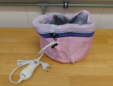 Electric Heating Cap A pink electric heating cap, with dark blue lining around the zip of the cap, and a plug attached