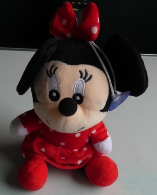 mouse_plush A small plush toy shaped like a cartoon-style mouse sitting upright. The toy wears a red outfit with white polka dots and a matching bow on the head. The plush has black ears, embroidered eyes, and a soft fabric texture. A small hanging loop with a suction cup is attached to the side of the head.