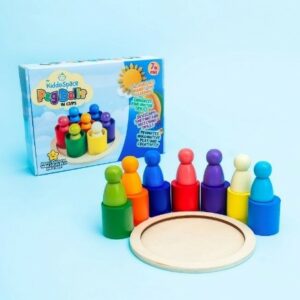 Peg Dolls in Cups Image shows Peg Dolls in Cups surrounding a small wooden platform. The dolls are situated in front of the product's packaging.